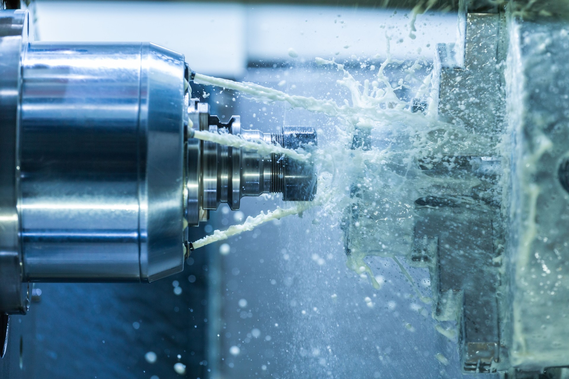 Vertical photo of industrial wet milling process with coolant flow under pressure and freezed splashes